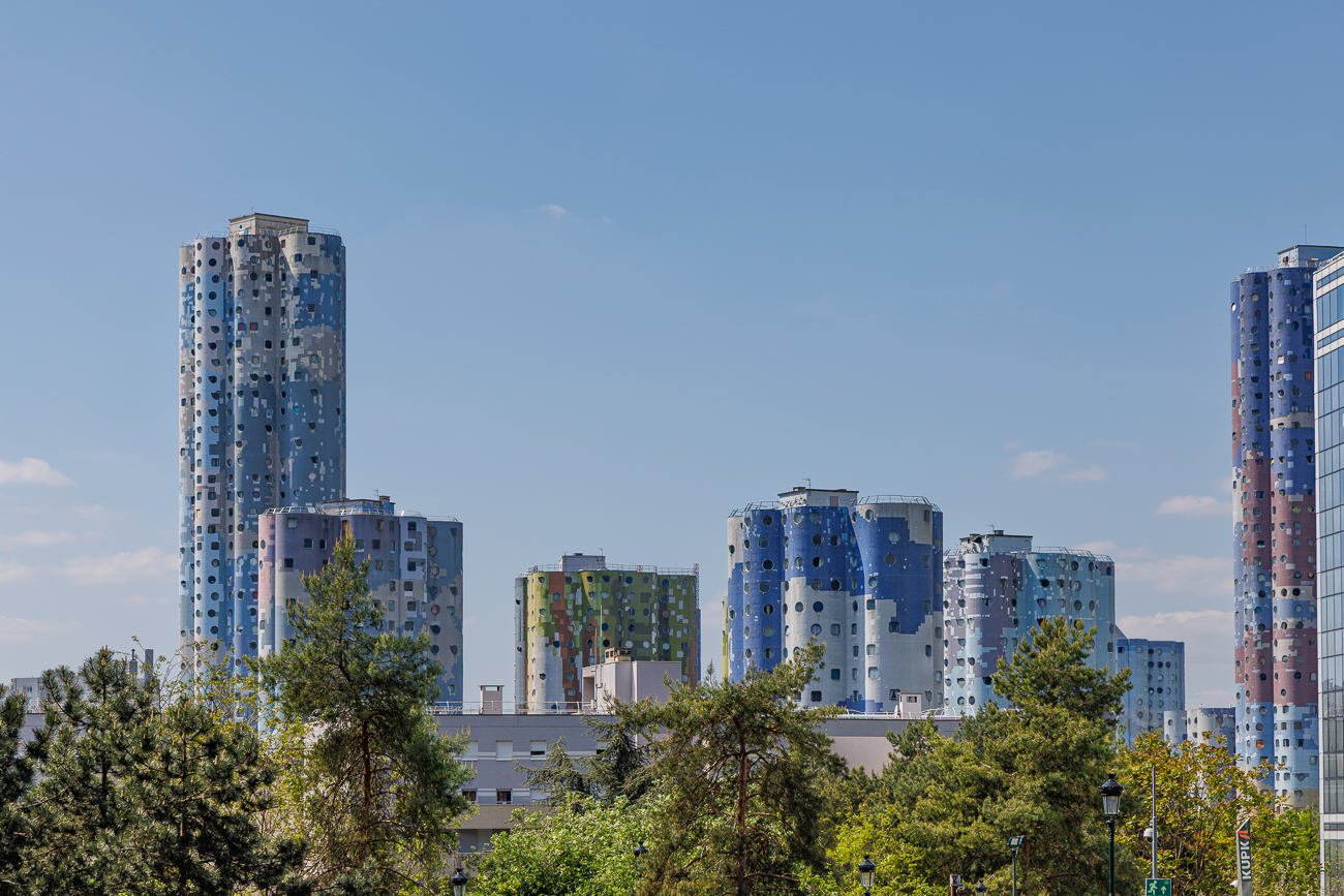 Die im Bild gezeigten Geb&auml;ude sind die Tours Aillaud, auch bekannt als Tours Nuages (Wolkent&uuml;rme) oder Cit&eacute; Pablo Picasso.Der Komplex besteht aus 18 Wohnhochh&auml;usern mit charakteristischen zylinderf&ouml;rmigen Grundrissen und Fassaden, die Fresken von Wolken darstellen